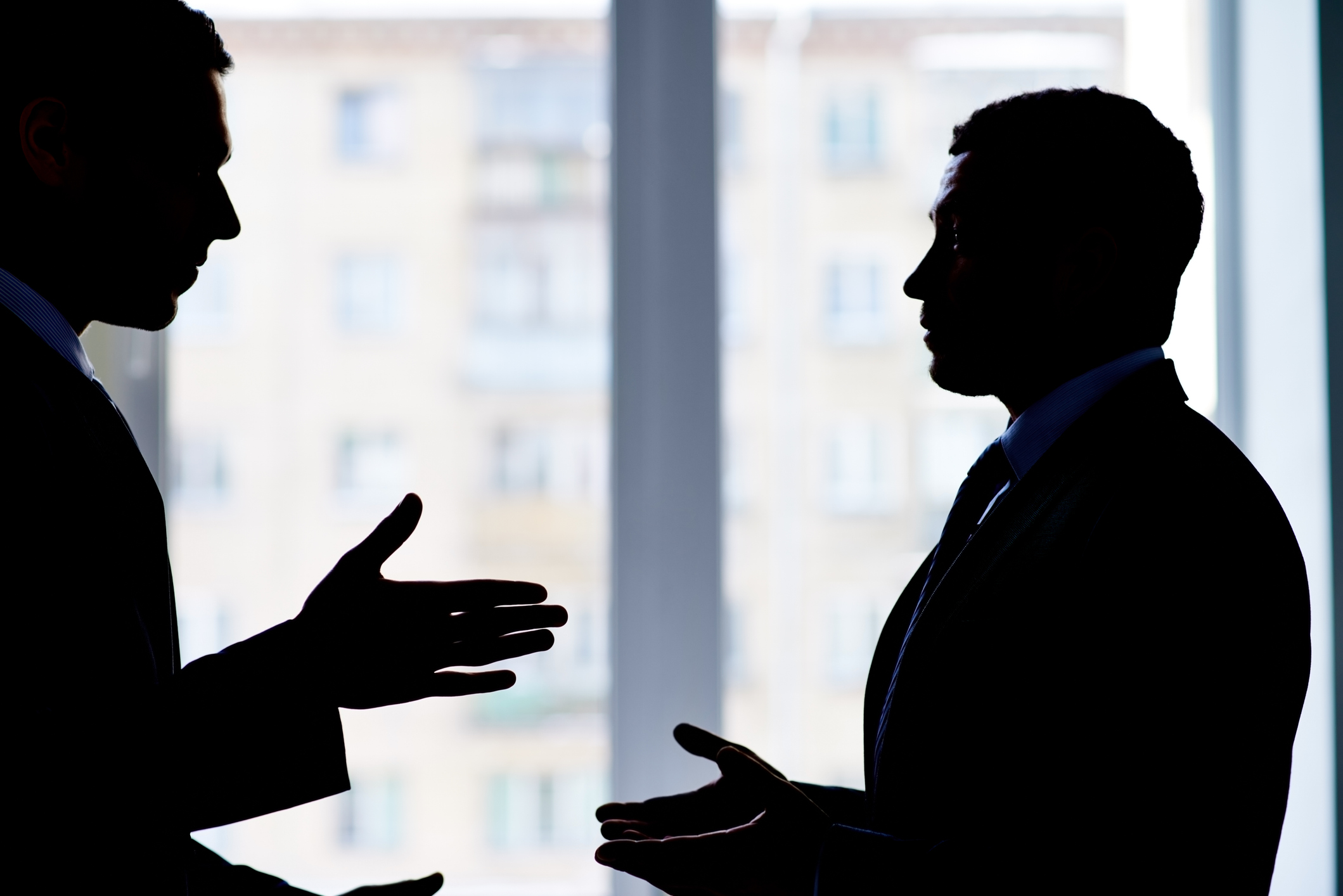 Back lit image of two businessmen